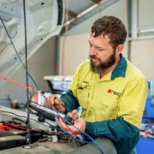Country Diesel Mechanics | A mechanic in a yellow and green shirt uses a diagnostic tool to check a vehicle's engine under the hood in a Northern Territory workshop, helping identify common vehicle problems and resolve vehicle issues efficiently. | Alice Springs